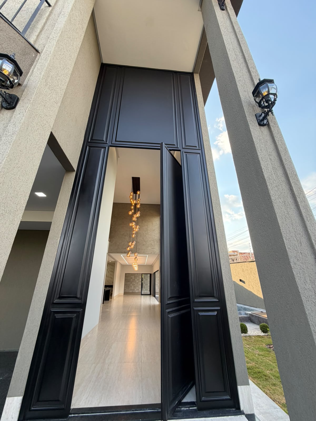Porta de entrada preta de grandes proporções com painéis decorativos